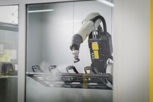 vollautomatisierter Lackierroboter lackiert Teile.JPG